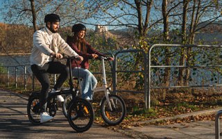 A commuter riding a folding e-bike in a UK city with greenery and eco-friendly urban surroundings.