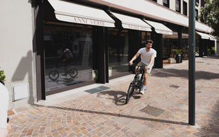 Commuter riding a folding electric bike on a long-distance route in the UK with integrated GPS and urban background