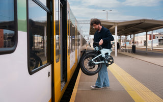 ADO Air 20 Ultra 2026 folding electric bike carried onto a train platform in the UK, compact folding ebike for multimodal commuting and urban travel