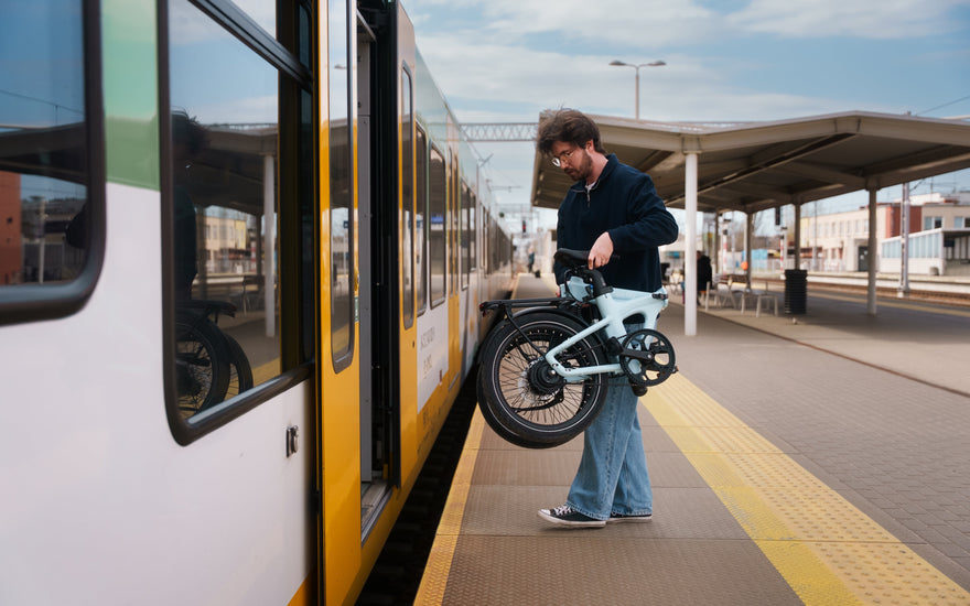 ADO Air 20 Ultra 2026 folding electric bike carried onto a train platform in the UK, compact folding ebike for multimodal commuting and urban travel