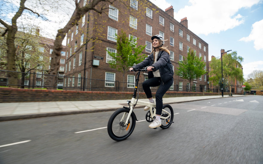 Student commuting on a folding electric bike near a UK university campus with compact dorm storage environment.